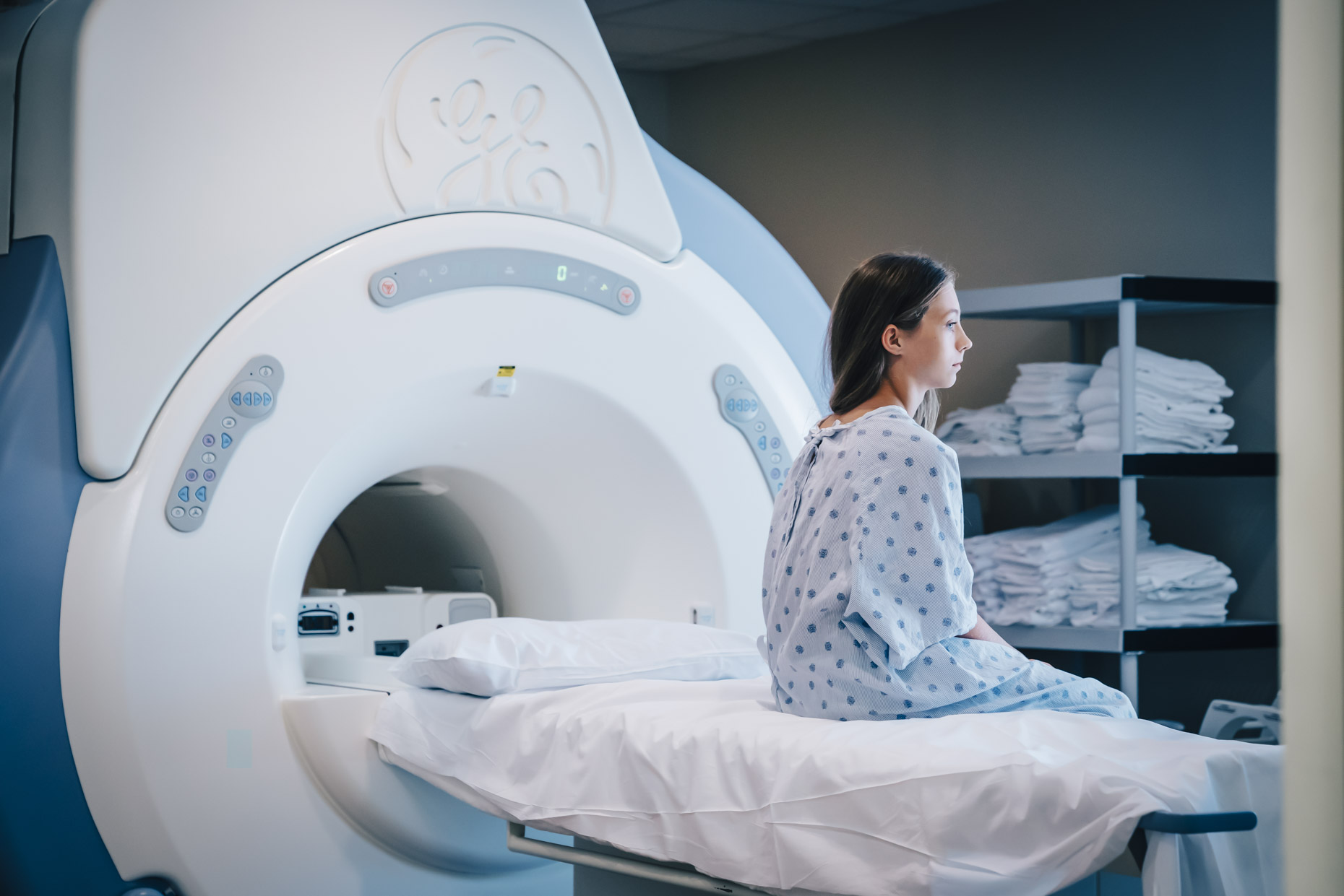 Sad teen girl sitting on MRI machine table