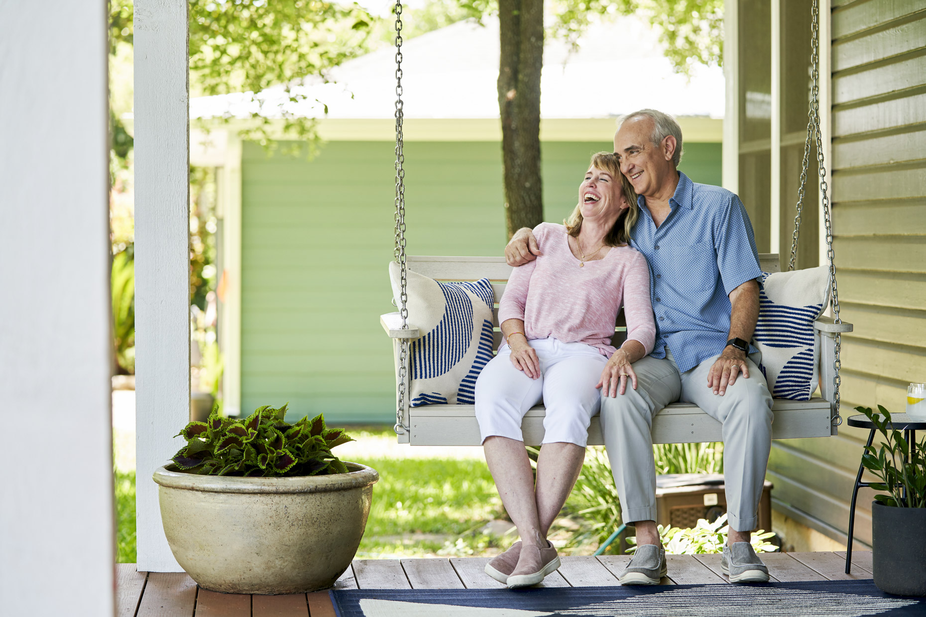 Senior couple sitting on porch swing laughing