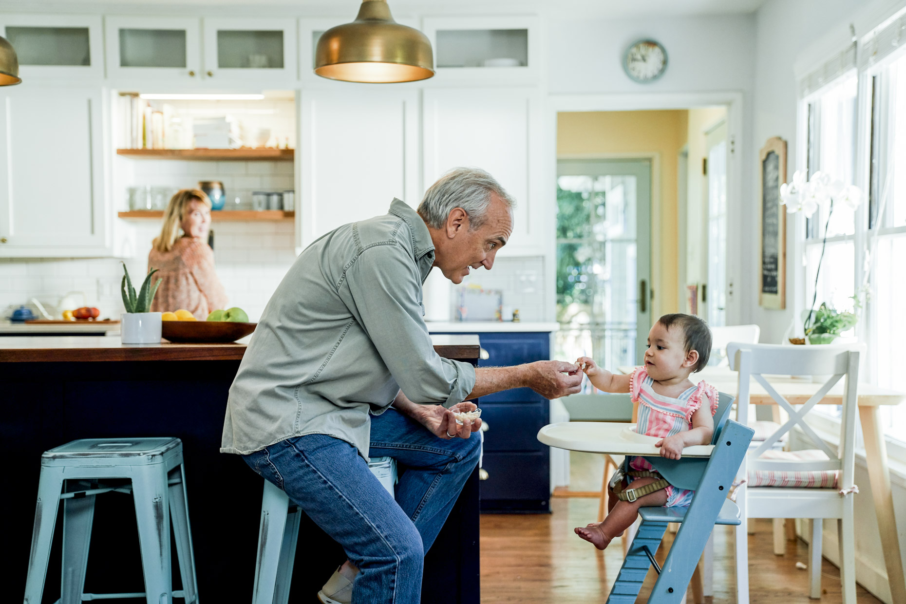 Senior-man-feeding-grandaughter-in-high-chair-in-kitchen-Mike_House_Kitchen_0075-Edit