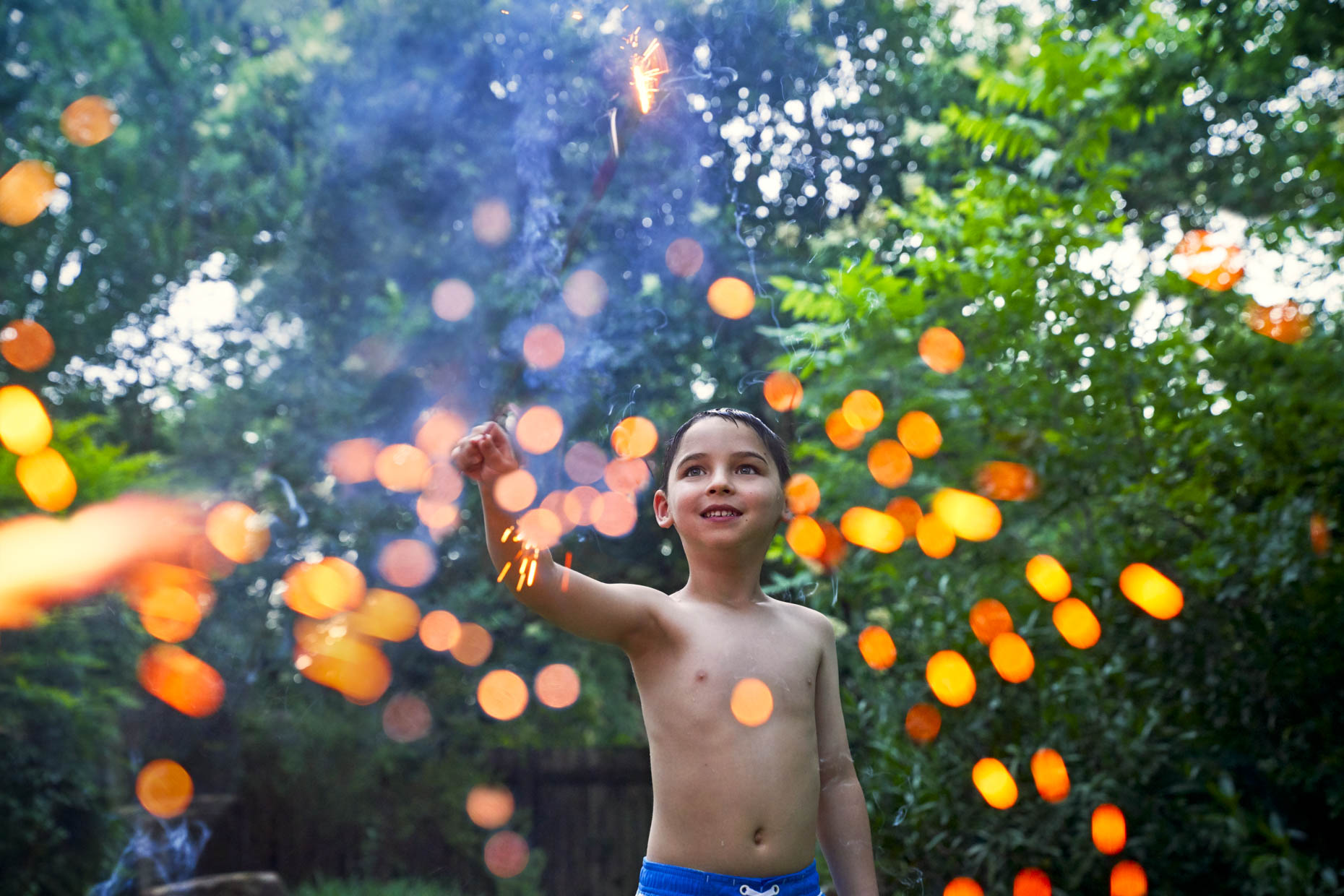 Shirtless-boy-playing-with-sparkler-outside-Inti-St-Clair-Lifestyle-John_House_Pool_1091-Edit