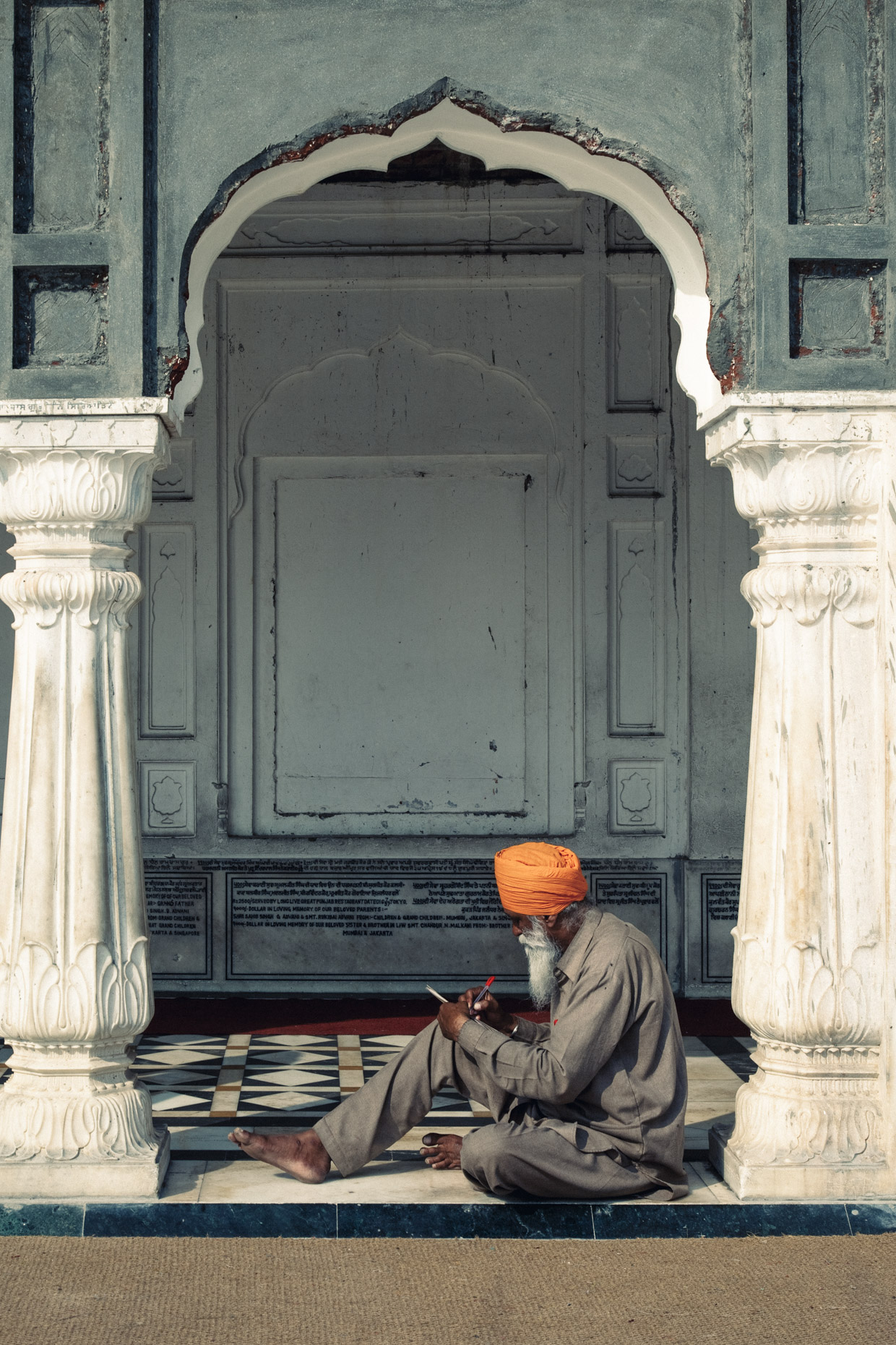 Sikh man in orange turbon sitting in doorway at golden temple in Amritsar, Punjab,  India