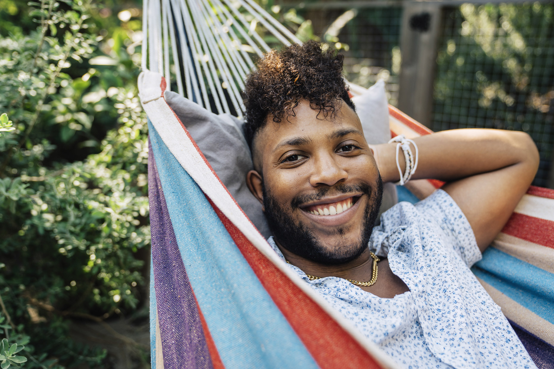 Smiling black man laying in hammock in back yard