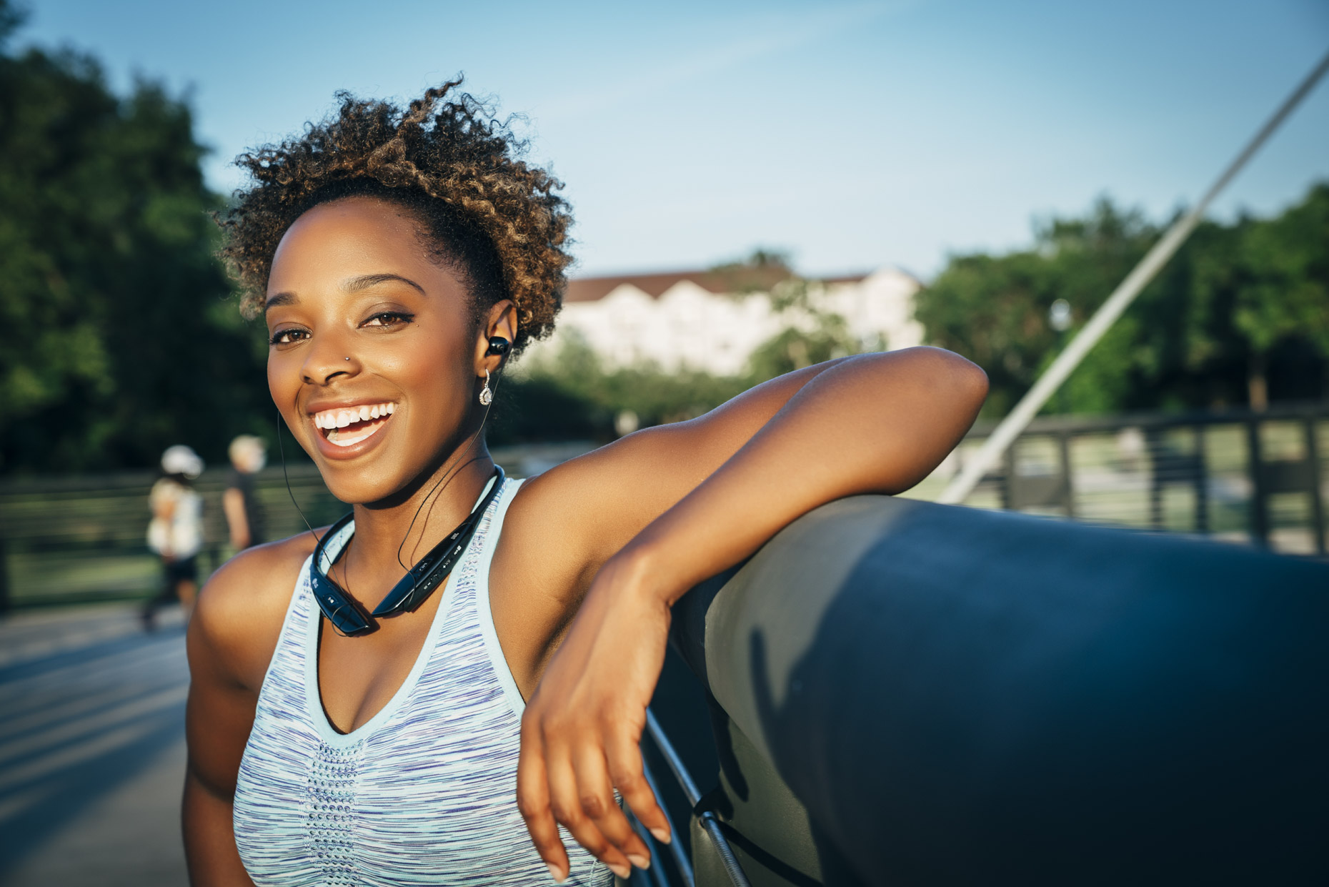Smiling black woman in fitness attire and wireless headphones