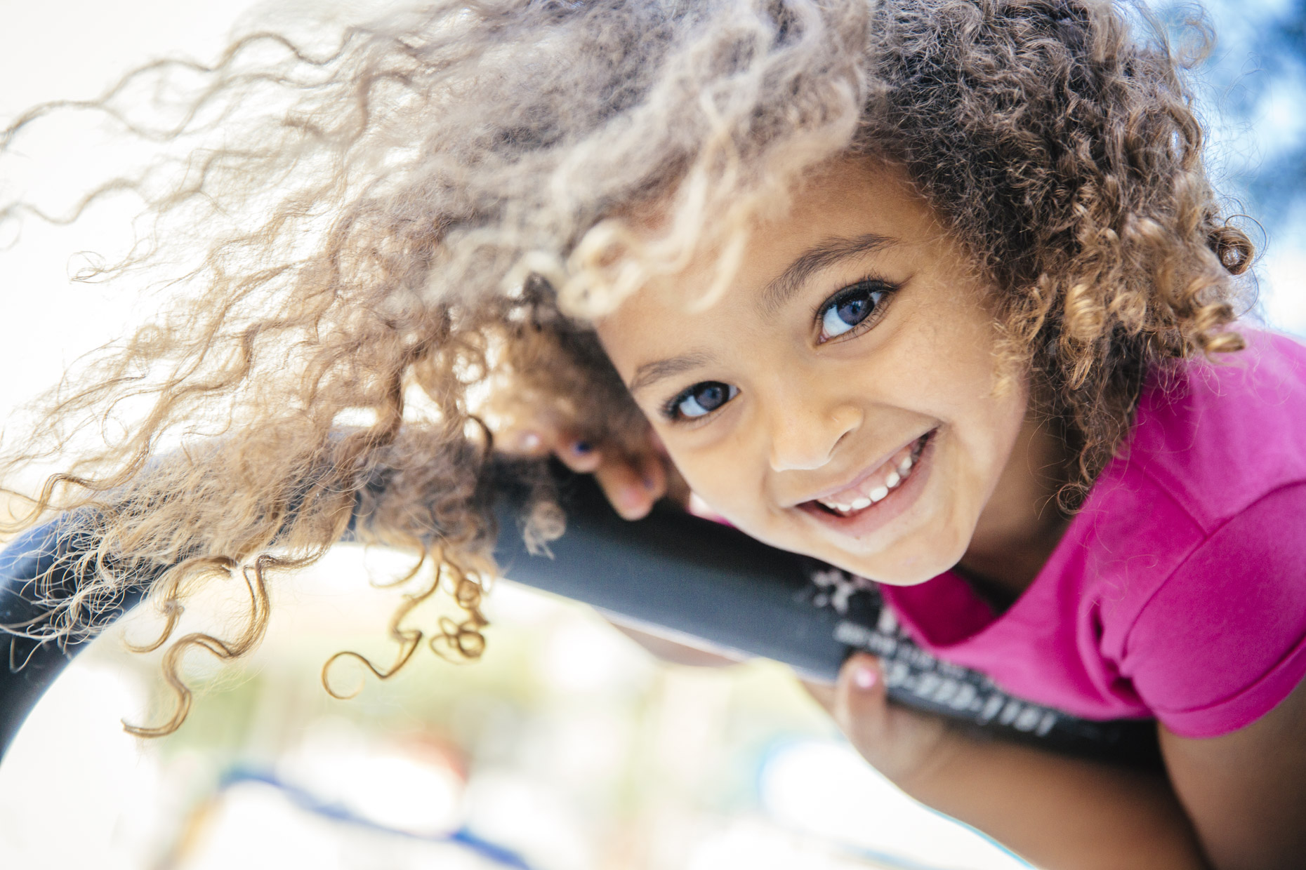Smiling girl with curly hair hanging upside down