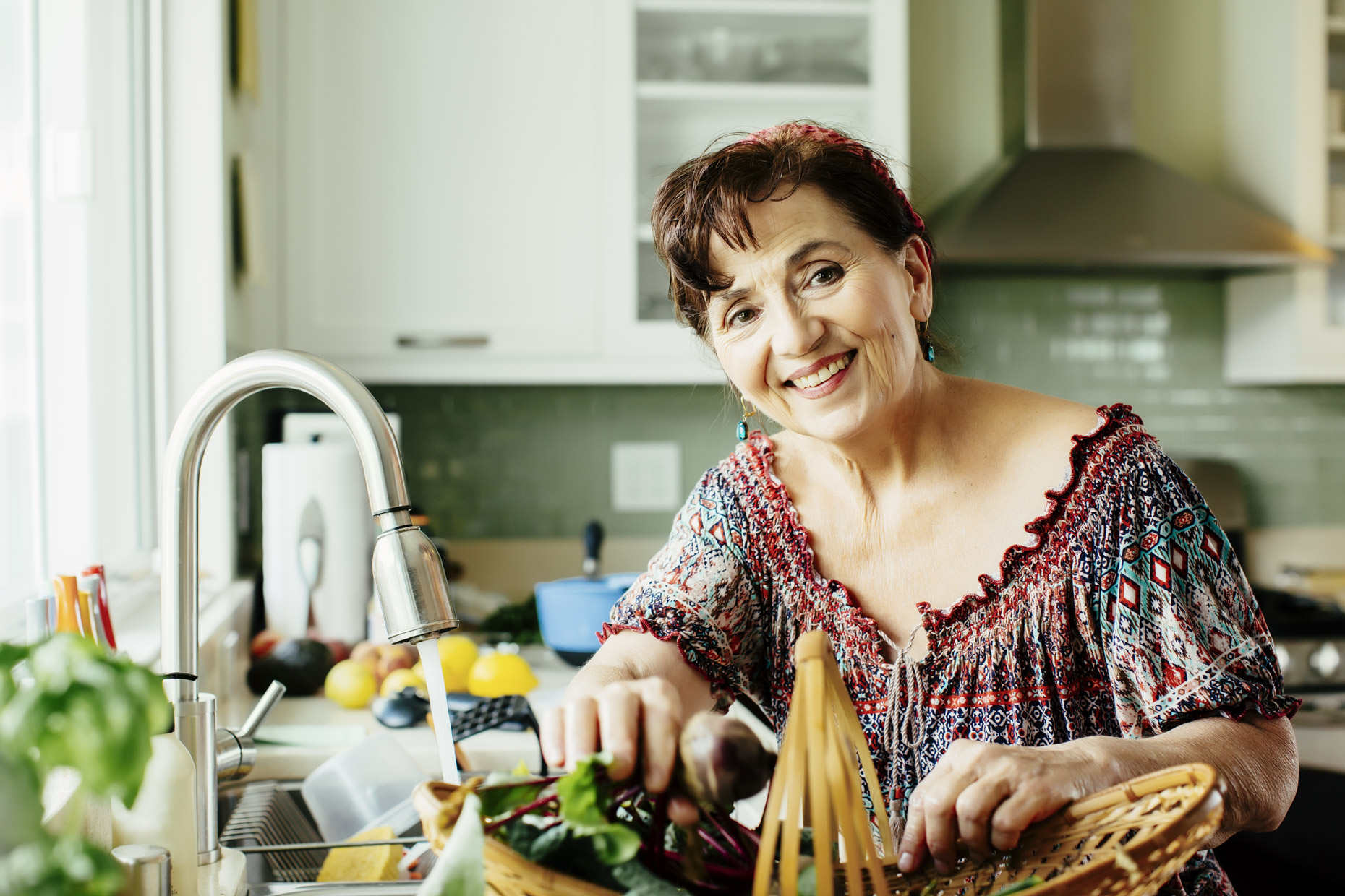 Smiling senior latinx woman in kitchen with vegetable basket