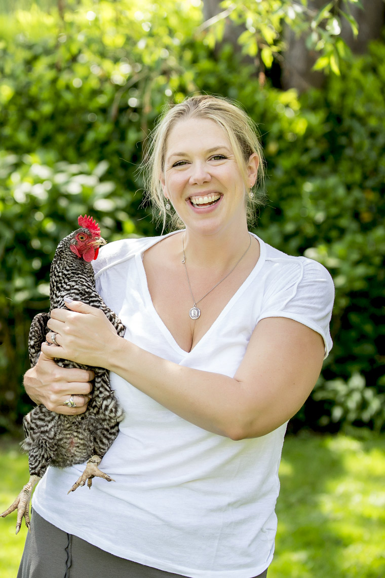 Smiling woman holding chickent in garden