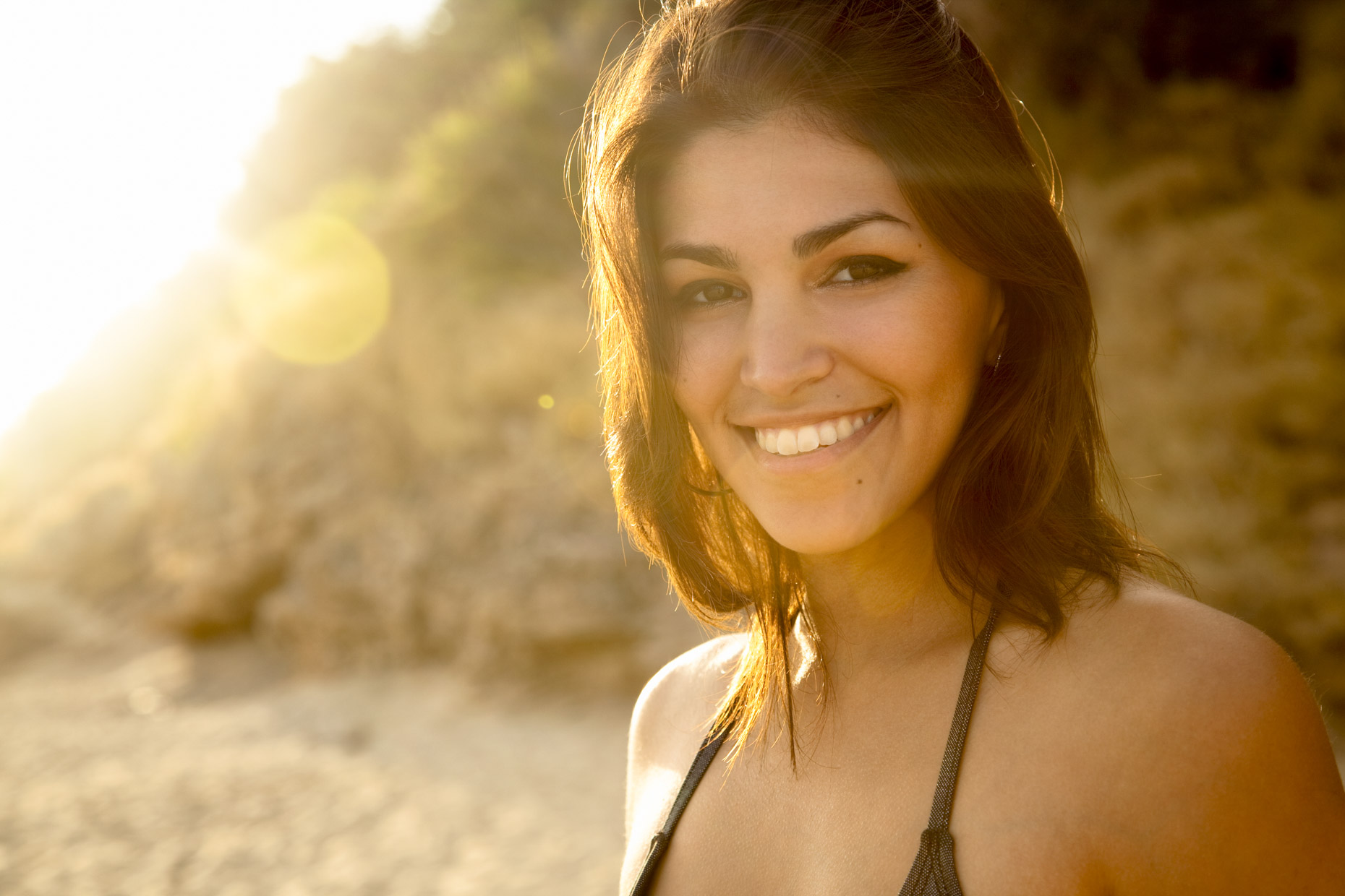 Smiling woman in sunlight on beach in bikini