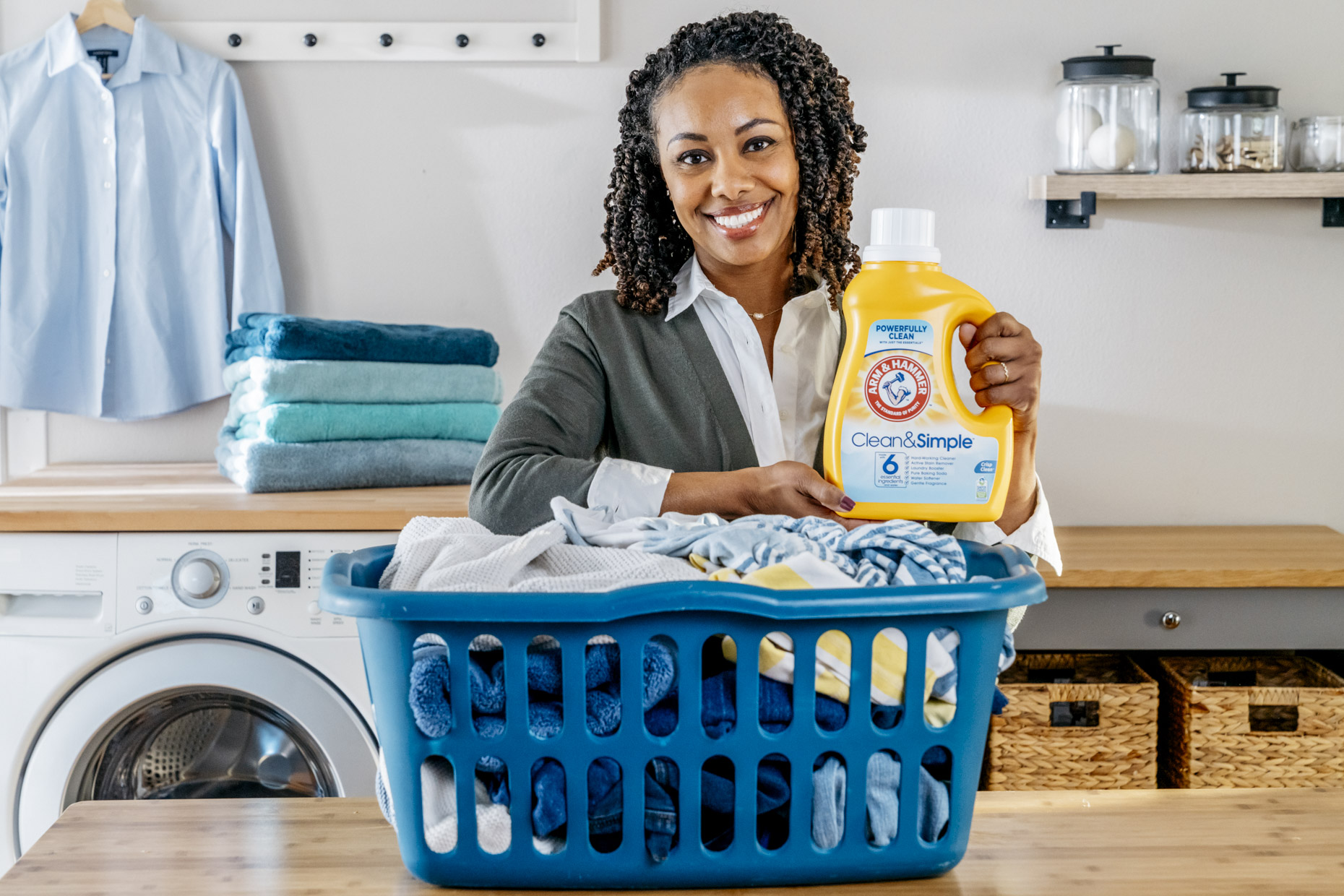 Smiling woman with bottle of Arm and Hammer detergent and basket of laundry