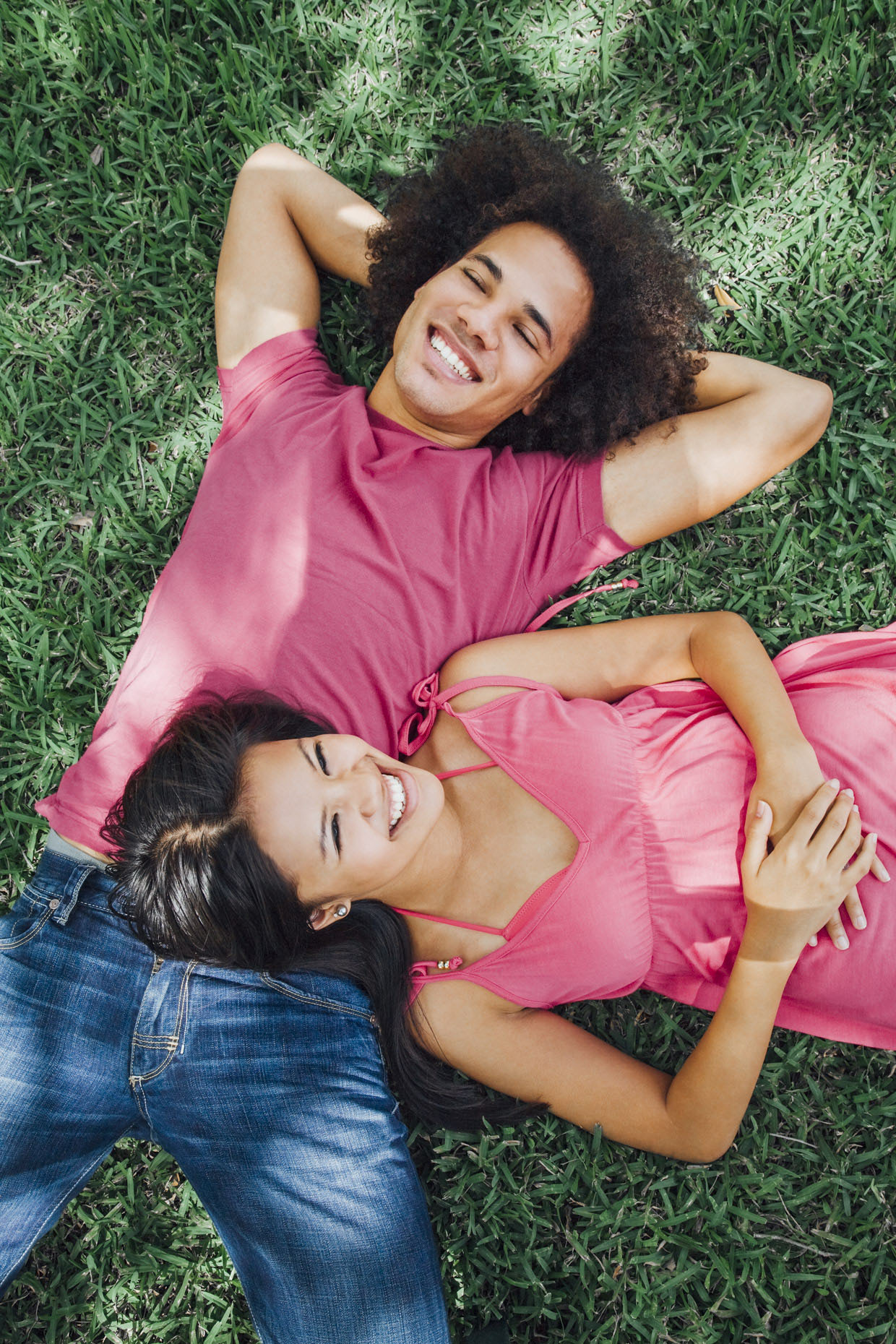 Teen boy and girl laying on grass laughing