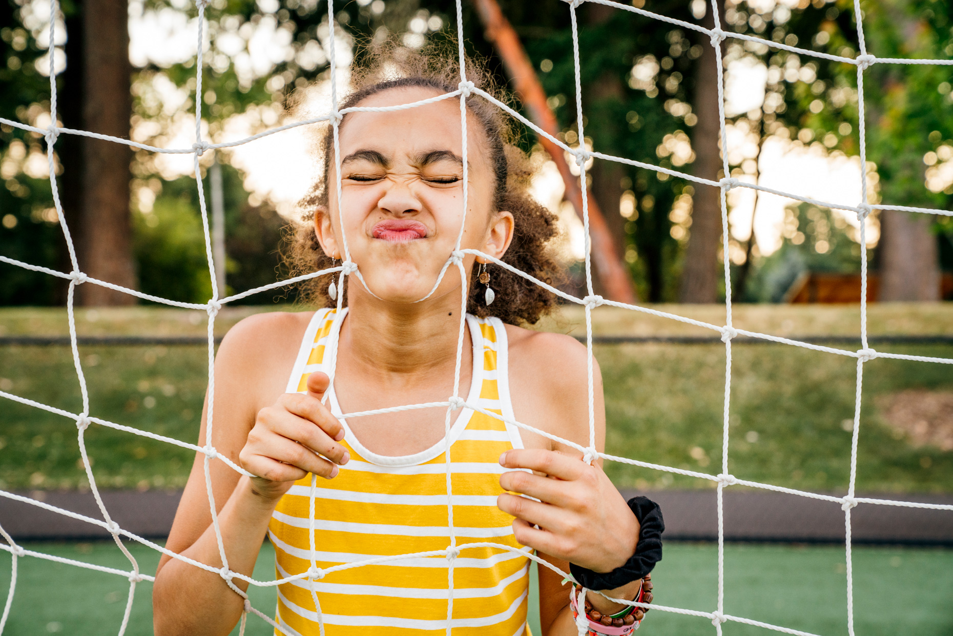 Teen-girl-with-face-in-soccer-goal-string-eyes-closed-20190630_NA_3081-2