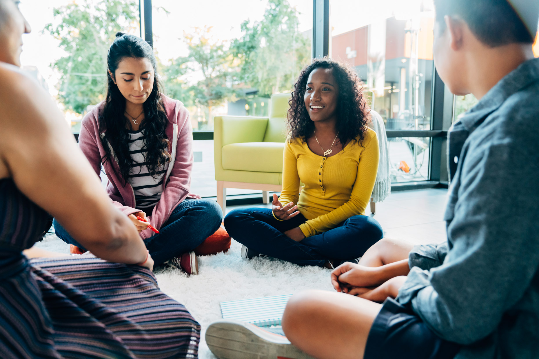Teens sitting in circle on floor in group therapy discussion