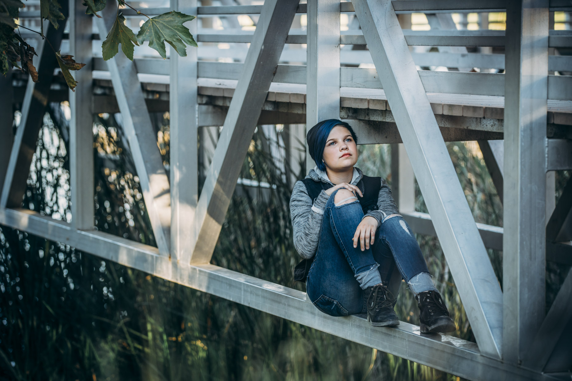 Transgender teen sitting under bridge looking up
