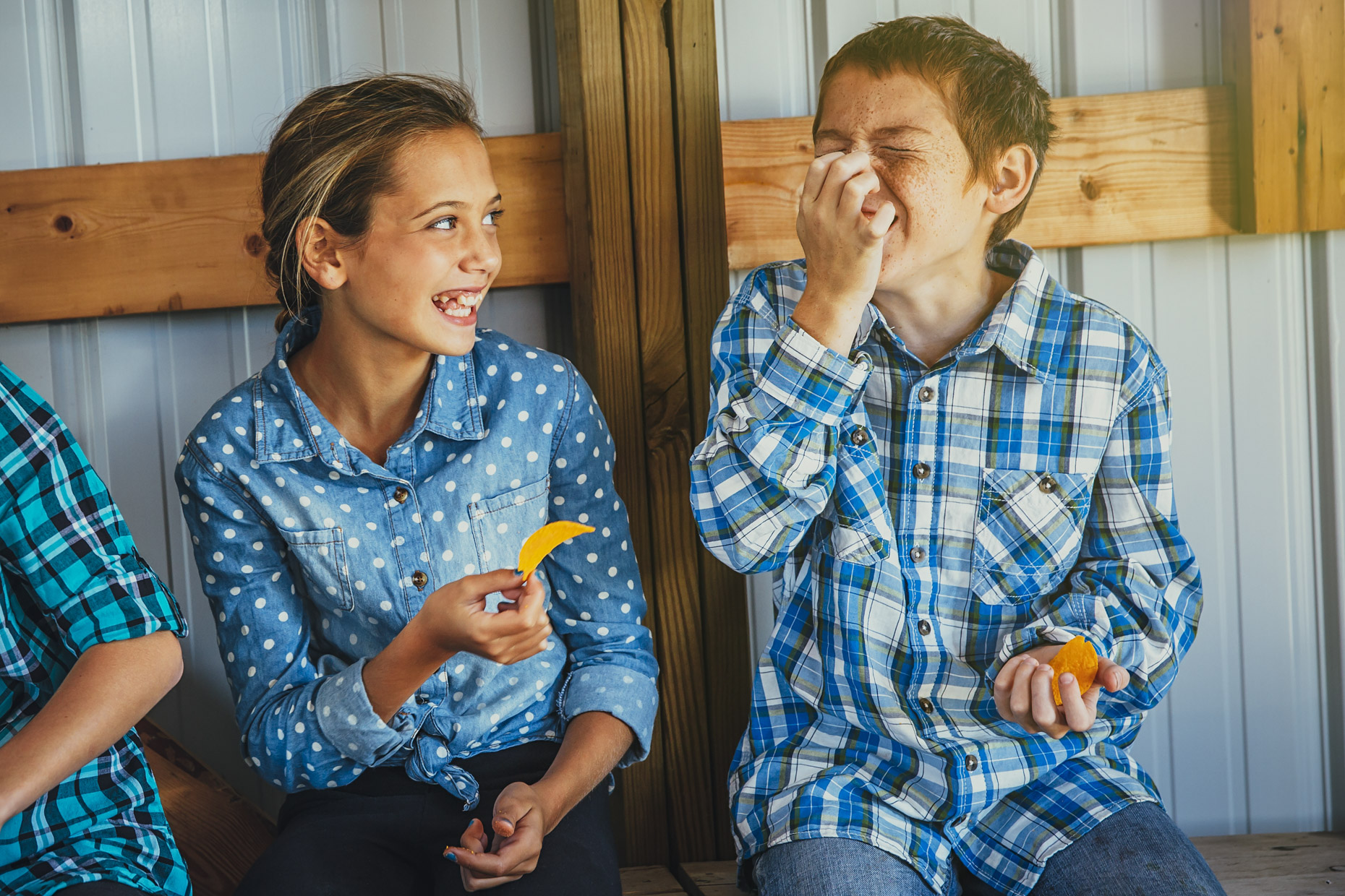 Tween boy and girl eating chips and laughing