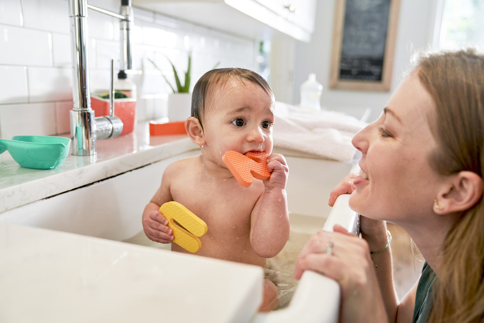 Woman bathing baby in kitchen sink