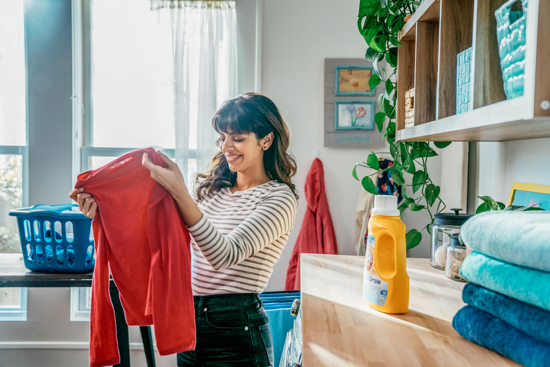 Woman holding up freshly washed shirt in laundry room