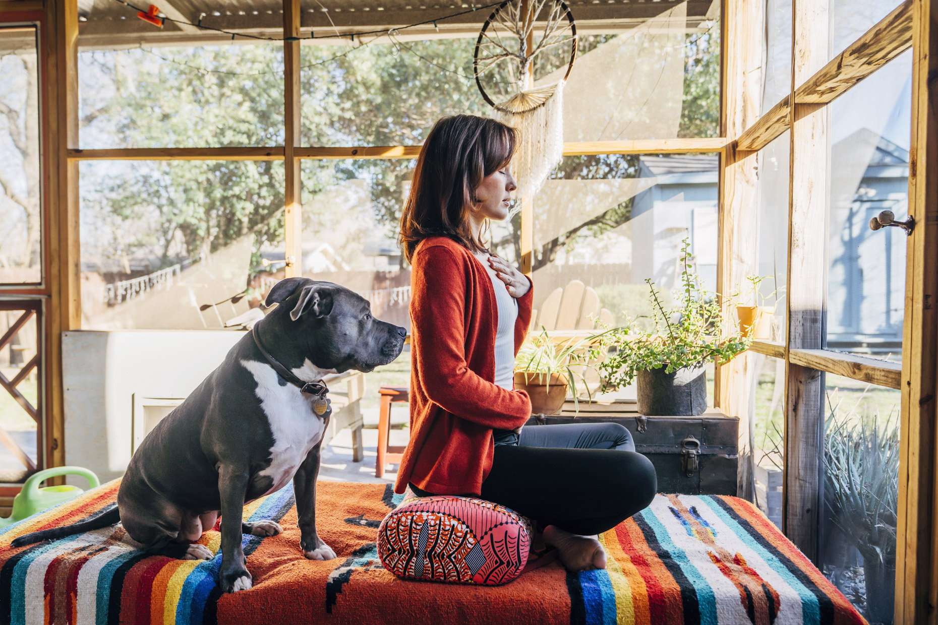 Woman meditating on porch with pitbull dog