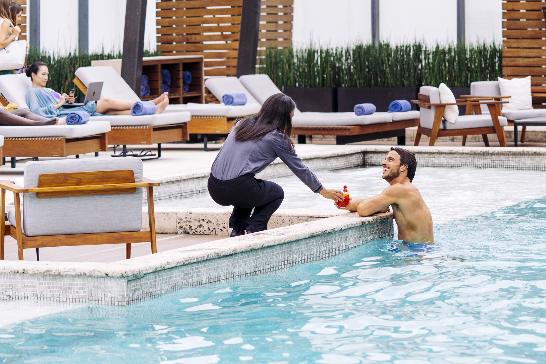 Woman serving man in hotel resort pool cocktail 