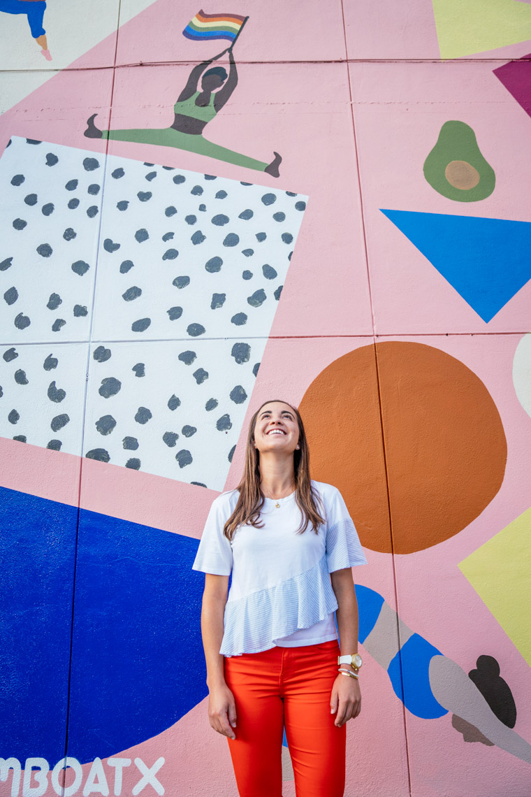 Woman standing in front of colorful wall mural looking up