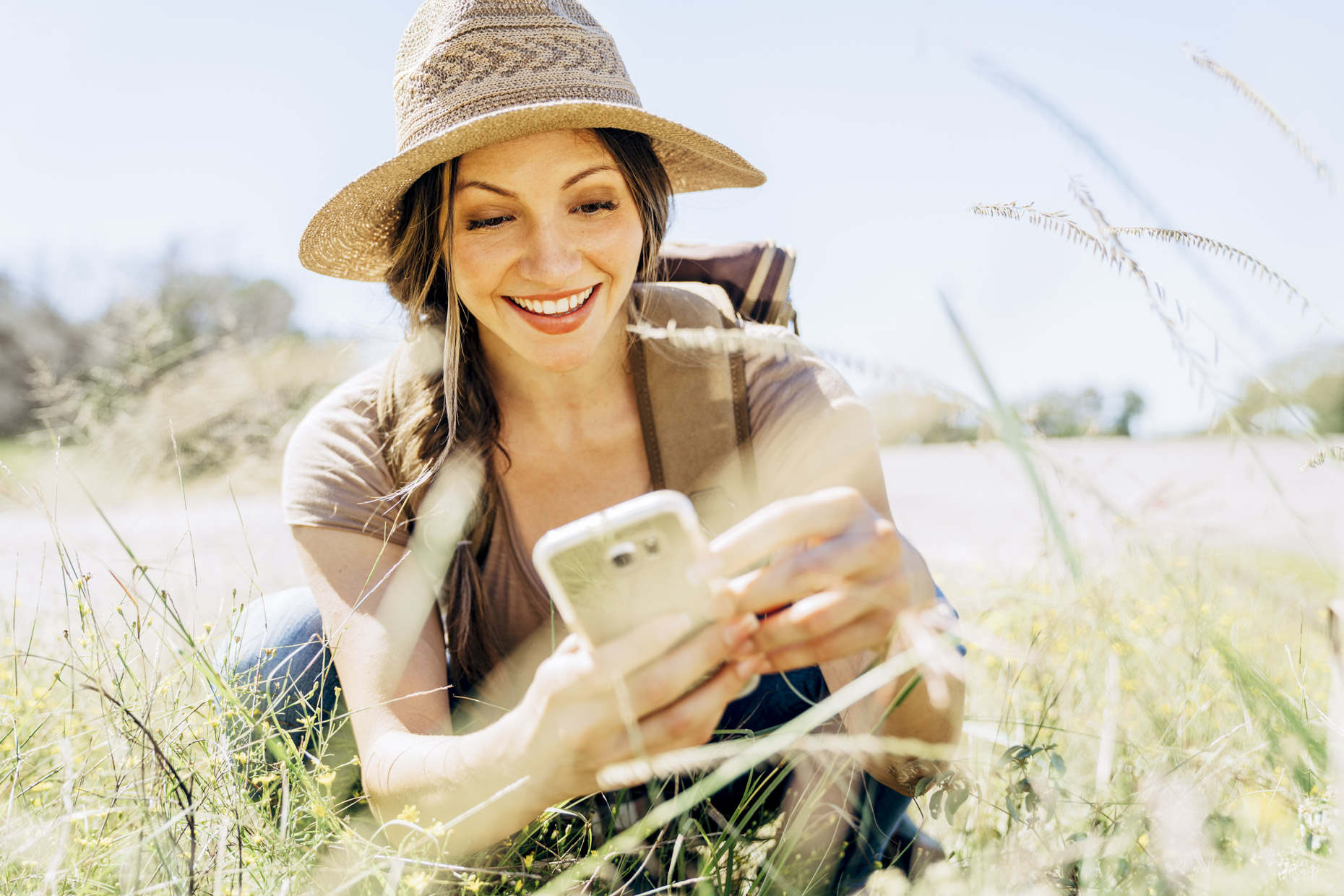 Woman in hat taking photo of nature with cell phone
