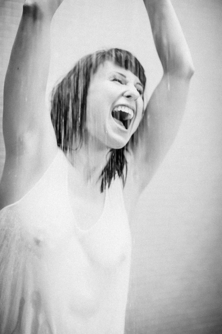 Woman with hands raised in the rain screaming in black and white