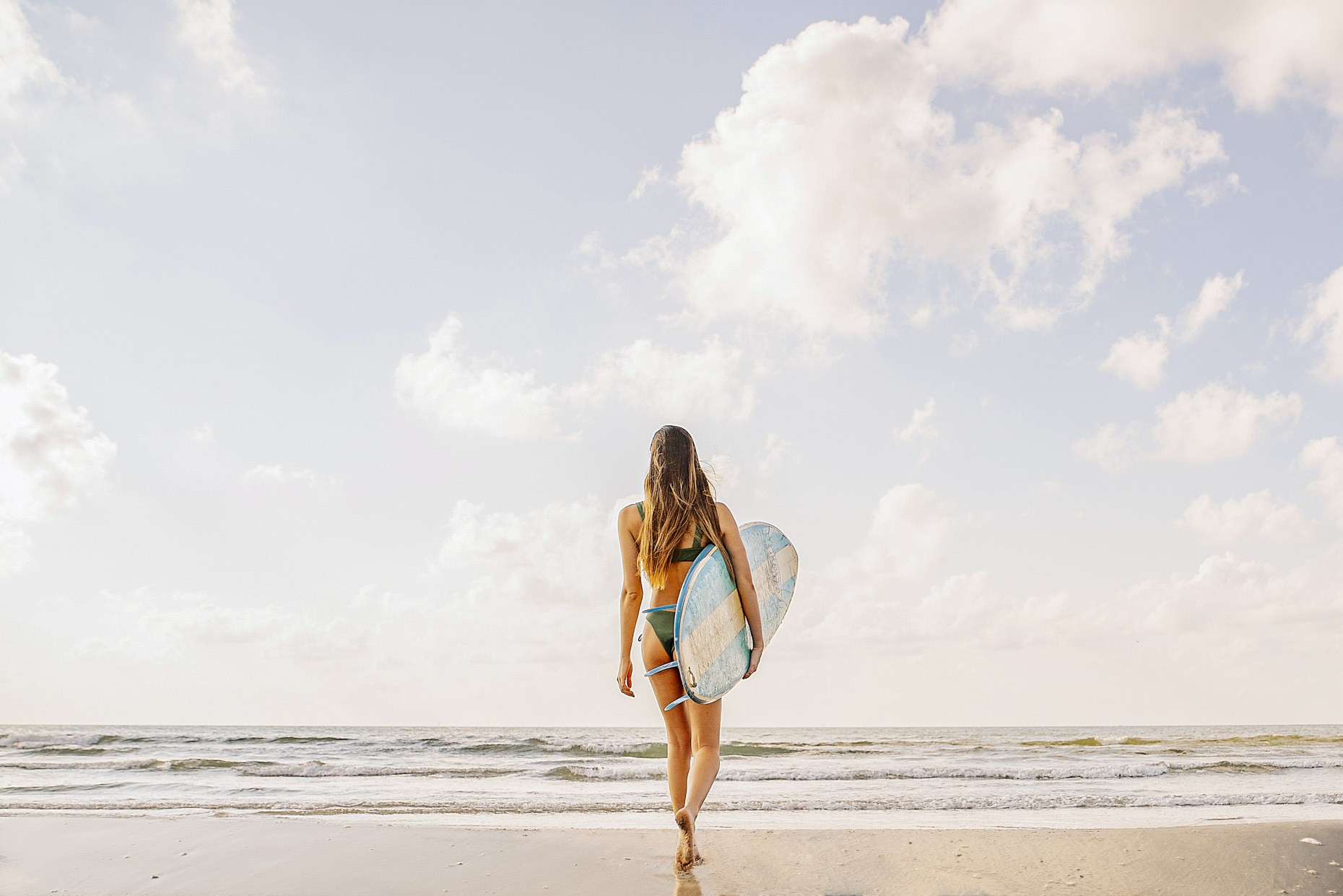 Woman walking with surfboard toward ocean