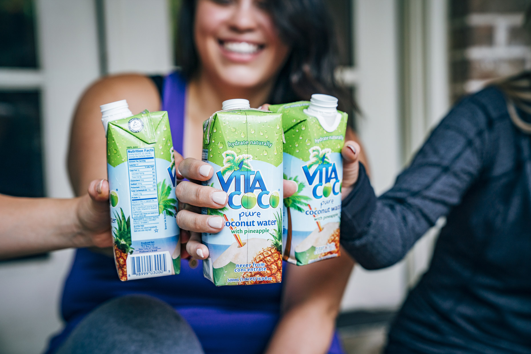Women in workout attire toasting with Vita Coco coconut water