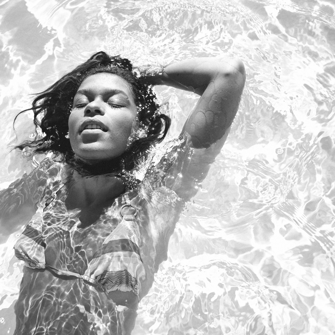 Black and white image of woman in bikini swimming in pool