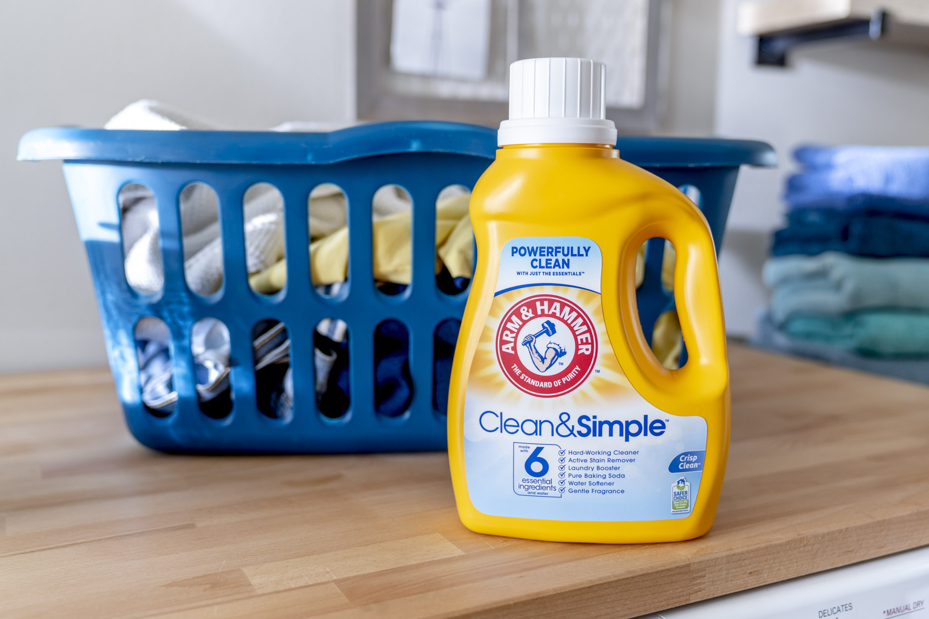 Bottle of Arm and Hammer detergent sitting on counter in front of laundry basket