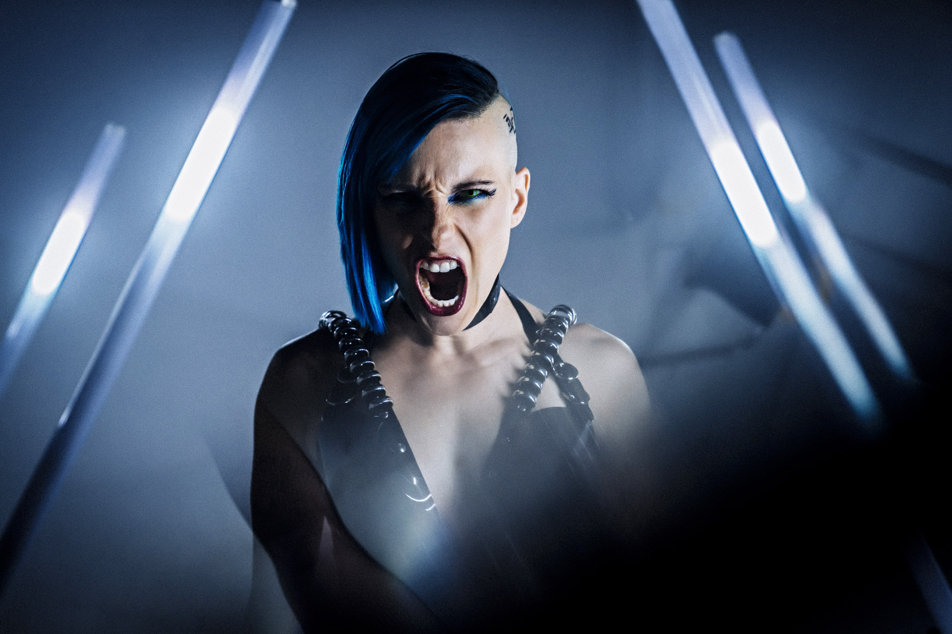 Cyber punk musician Le Destroy with blue hair screaming toward camera