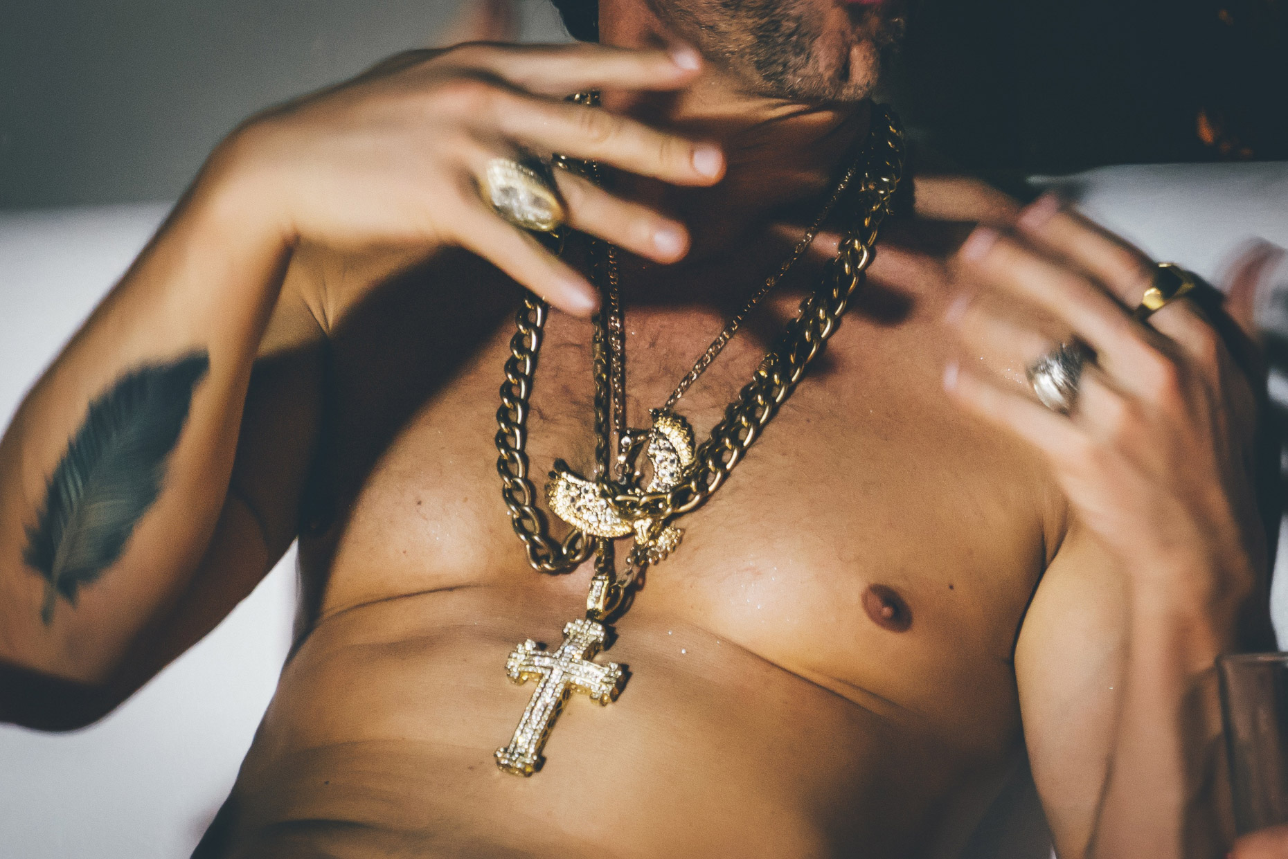 Naked male torso wearing diamond and gold necklaces with cross and eagle charms