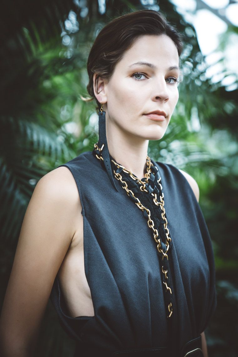 Portrait of woman wearing necklace earrings of brass and black leather