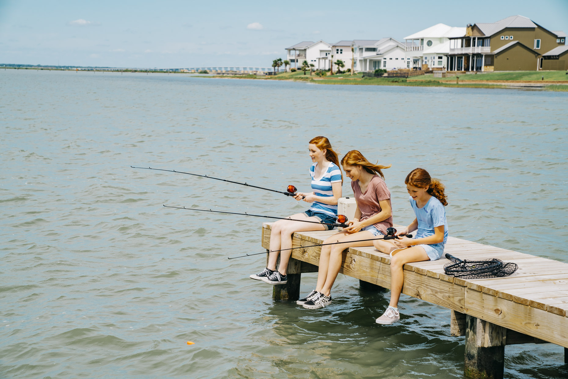 Three red haired girls fishing from dock in ocean