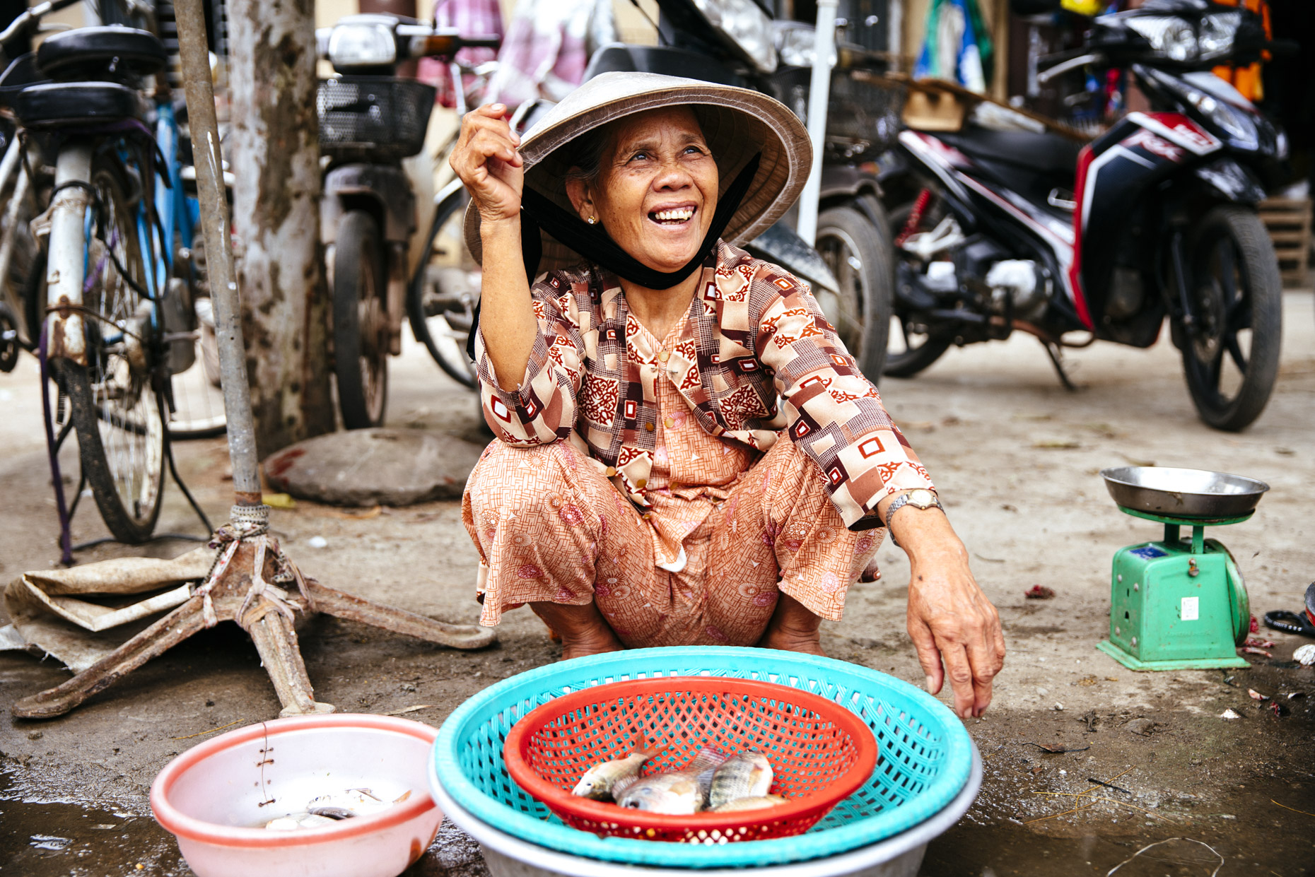Smiling Vietnamese woman selling fish on street