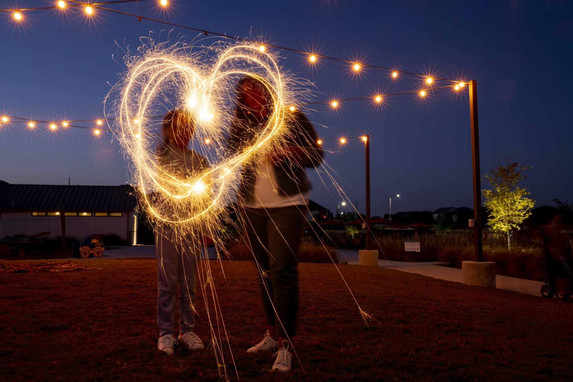 Woman and girl making heart with sparklers at night